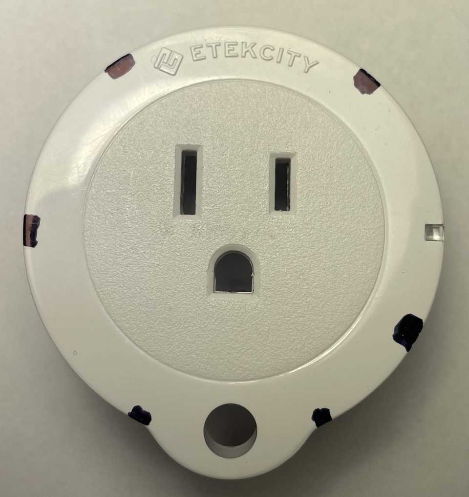 A top-down front view of an Etekcity Voltson ESW01-USA-R6P Smart Outlet. The outlet, button, and LED indicator are facing the viewer. Black marks around the circumference of the plug indicate the locations of the six clips of the plastic shell. The markings are positioned clockwise at 40°, 120°, 155°, 205°, 270°, and 325°.